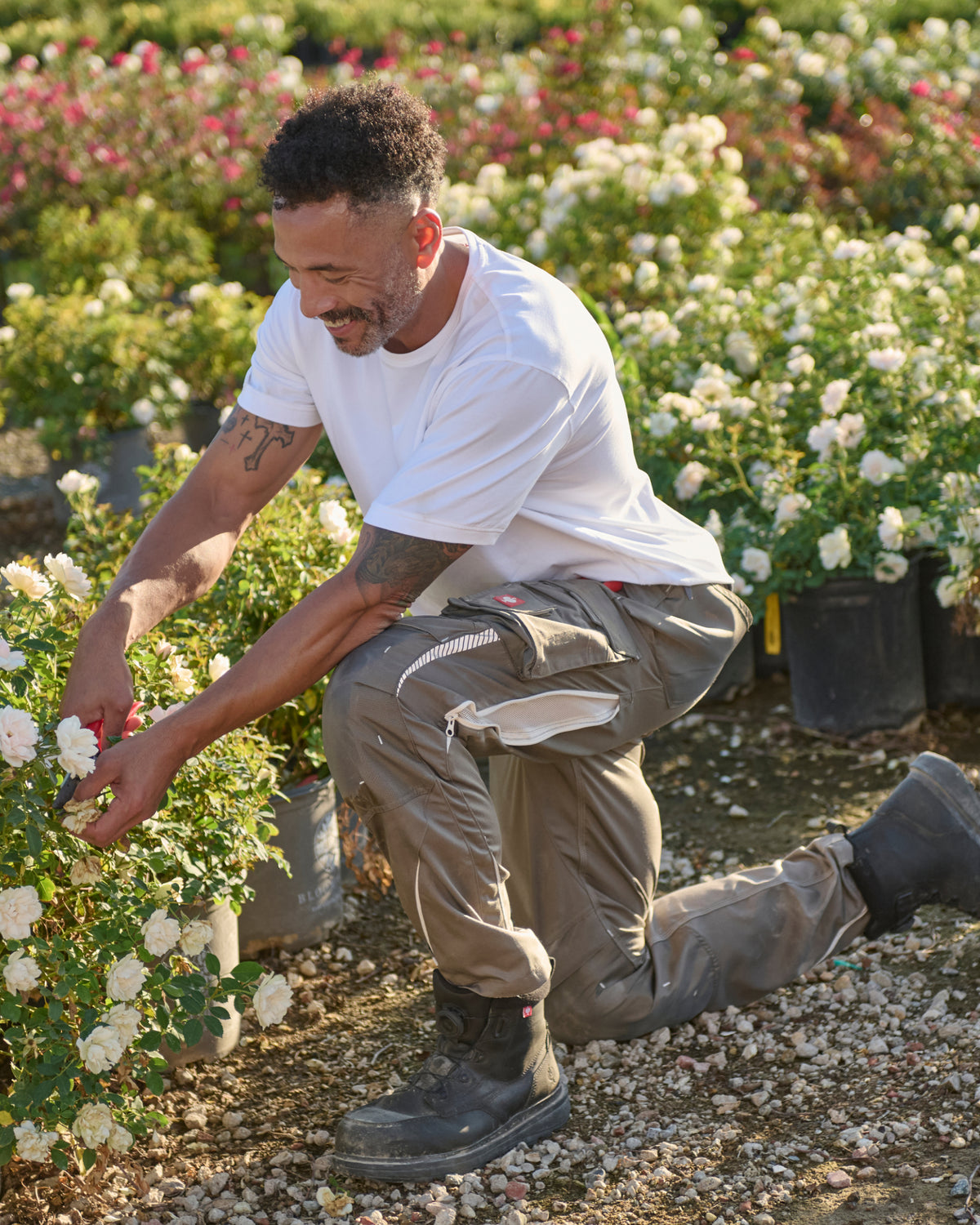 A worker wears the STRAUSS Cotton T-Shirt in white with tan work pants on a sunny field