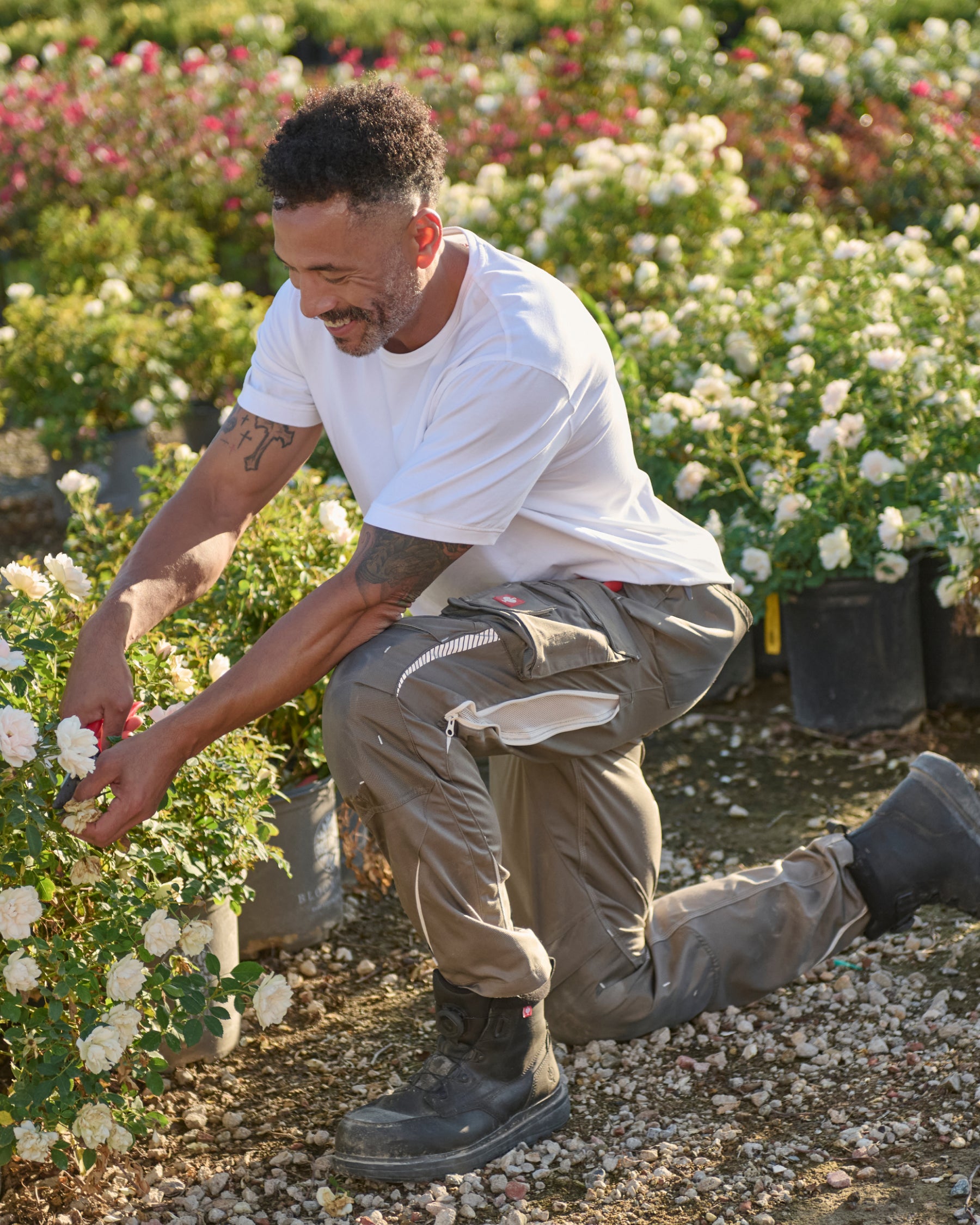 A worker wears the STRAUSS Cotton T-Shirt in white with tan work pants on a sunny field