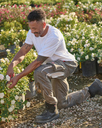 A worker wears the STRAUSS Cotton T-Shirt in white with tan work pants on a sunny field