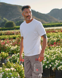 A worker wears the STRAUSS Cotton T-Shirt in white with tan work pants while working in a field