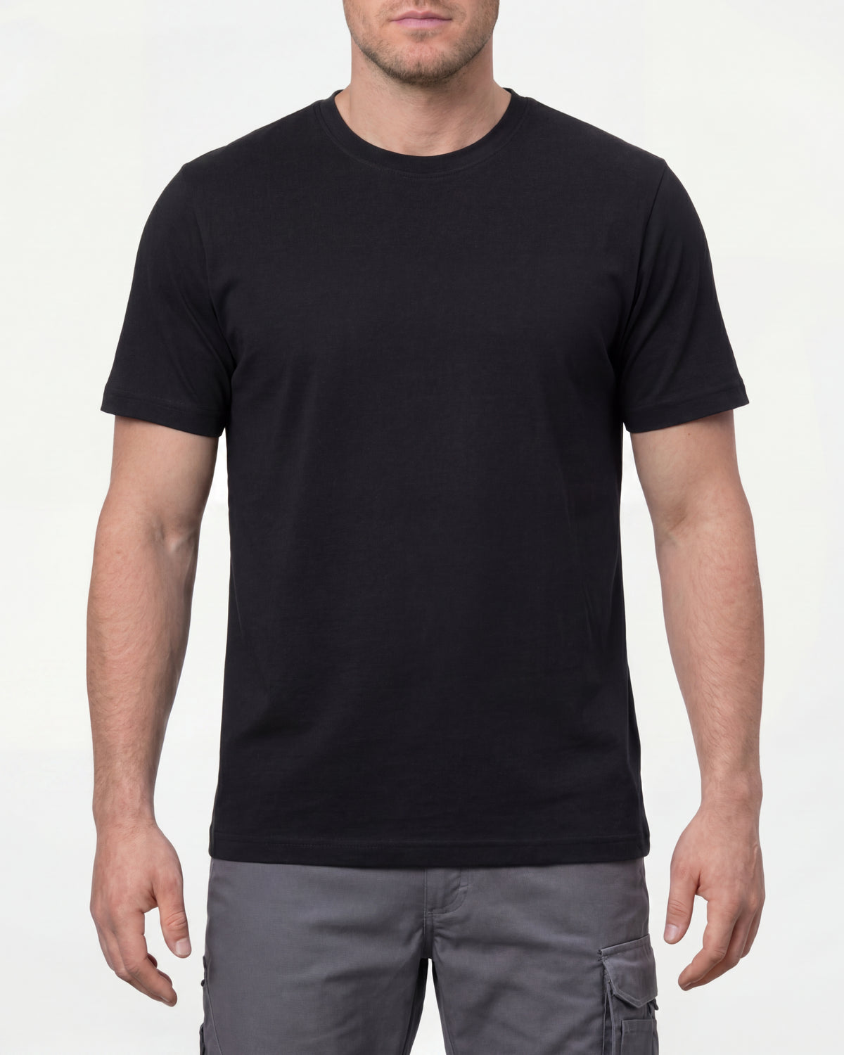A model wears the STRAUSS Cotton T-Shirt in black with tan work pants and work boots in a studio product scene