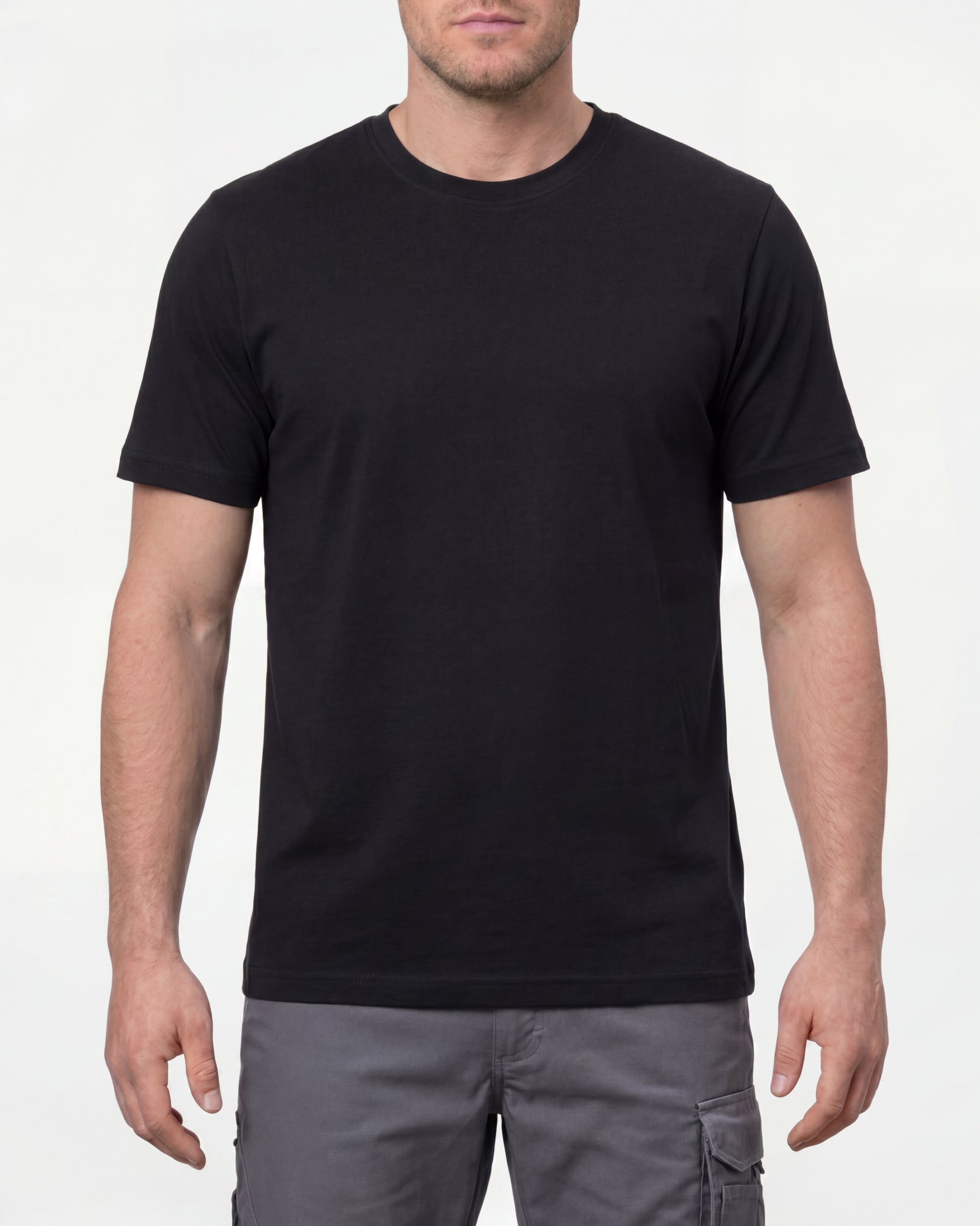 A model wears the STRAUSS Cotton T-Shirt in black with tan work pants and work boots in a studio product scene