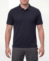 A model wears the STRAUSS Cotton Polo Shirt in nero blue with tan work pants and work boots in a studio product scene