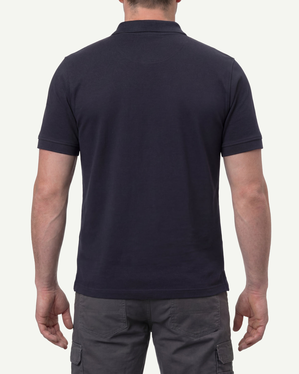 A model wears the STRAUSS Cotton Polo Shirt in nero blue with tan work pants and work boots, showing the shirt fit
