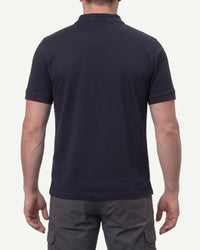 A model wears the STRAUSS Cotton Polo Shirt in nero blue with tan work pants and work boots, showing the shirt fit