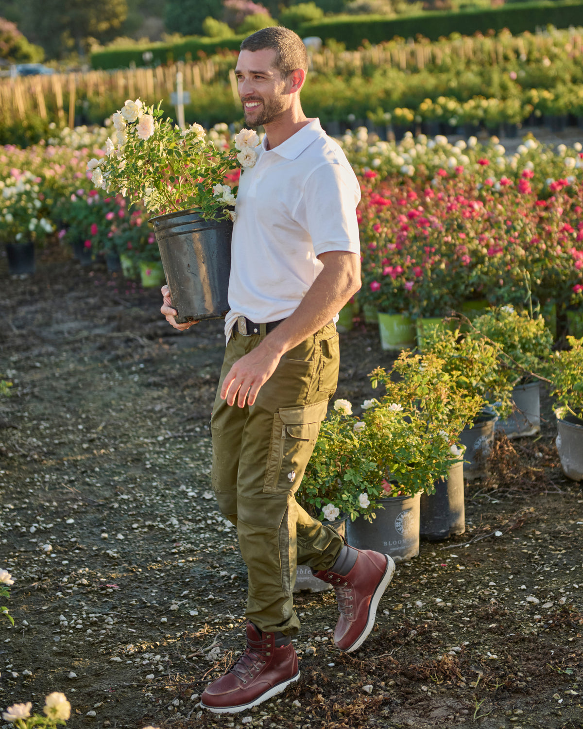 A worker wears the STRAUSS Cotton Polo Shirt in white with tan work pants while working in a field