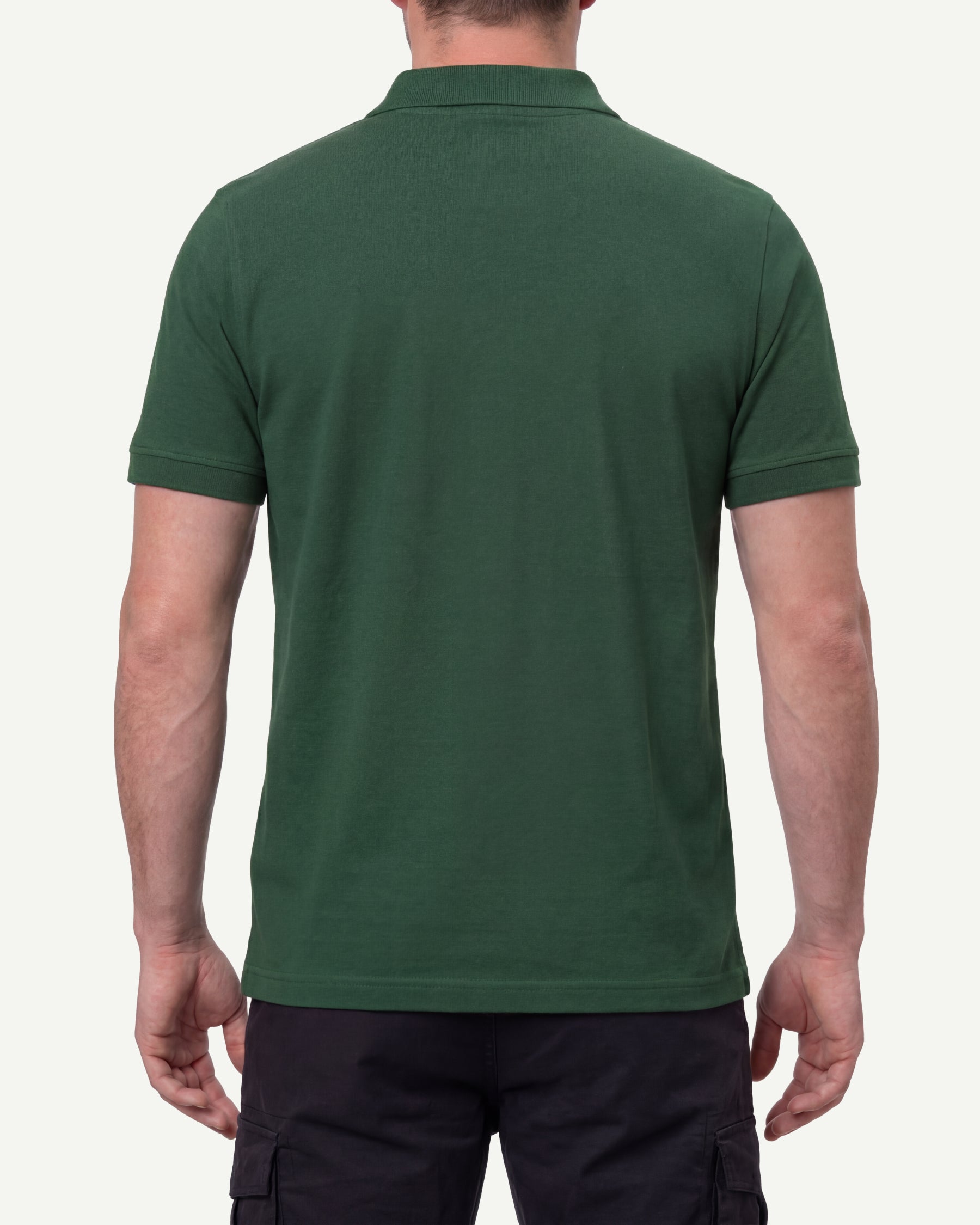 A model wears the STRAUSS Cotton Polo Shirt in green with tan work pants and work boots, showing the shirt fit