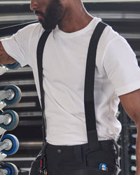 A worker wears black STRAUSS e.s.taktik Y-back suspenders over a work shirt with utility pants.