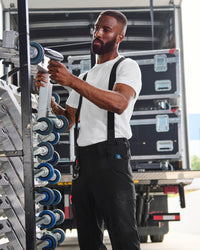 A model wears black STRAUSS e.s.taktik Y-back suspenders with a rugged workwear outfit.