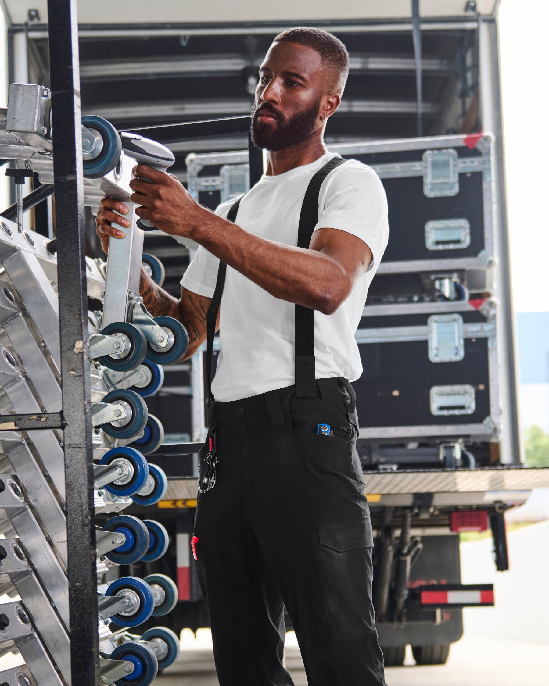 A model wears black STRAUSS e.s.taktik Y-back suspenders with a rugged workwear outfit.