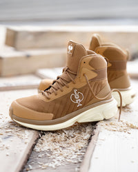 A pair of tan and brown high-top athletic sneakers with a white sole, featuring a white rooster logo on the side and tongue, displayed on weathered wooden planks outdoors.