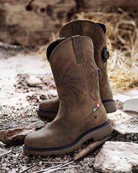 STRAUSS Doonan 12-inch Composite Toe Work Boot in Brown shown on rough jobsite ground