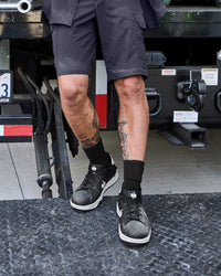 STRAUSS Philly Steel Toe Work Shoe in Black and White shown on rough jobsite ground