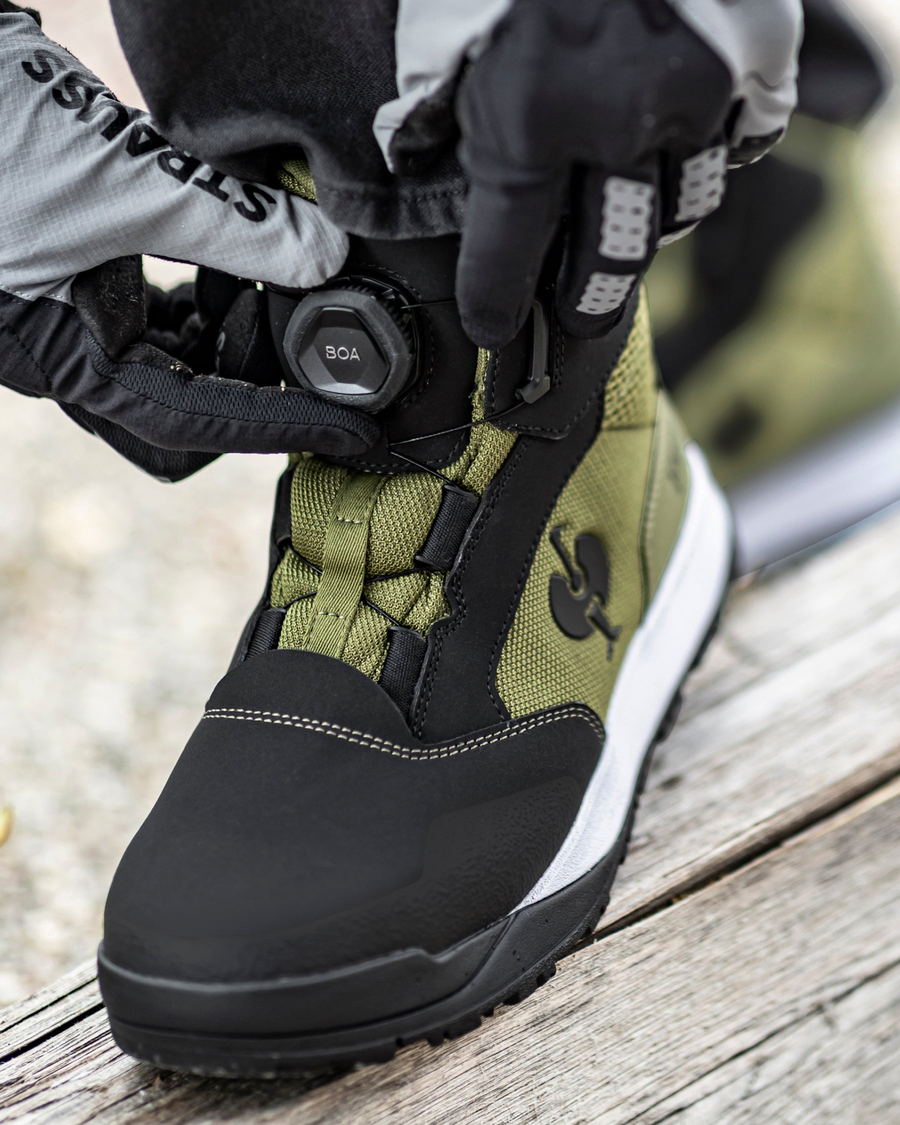 STRAUSS Murcia 6-inch Steel Toe Work Boot in Black and Mountain green shown on rough jobsite ground
