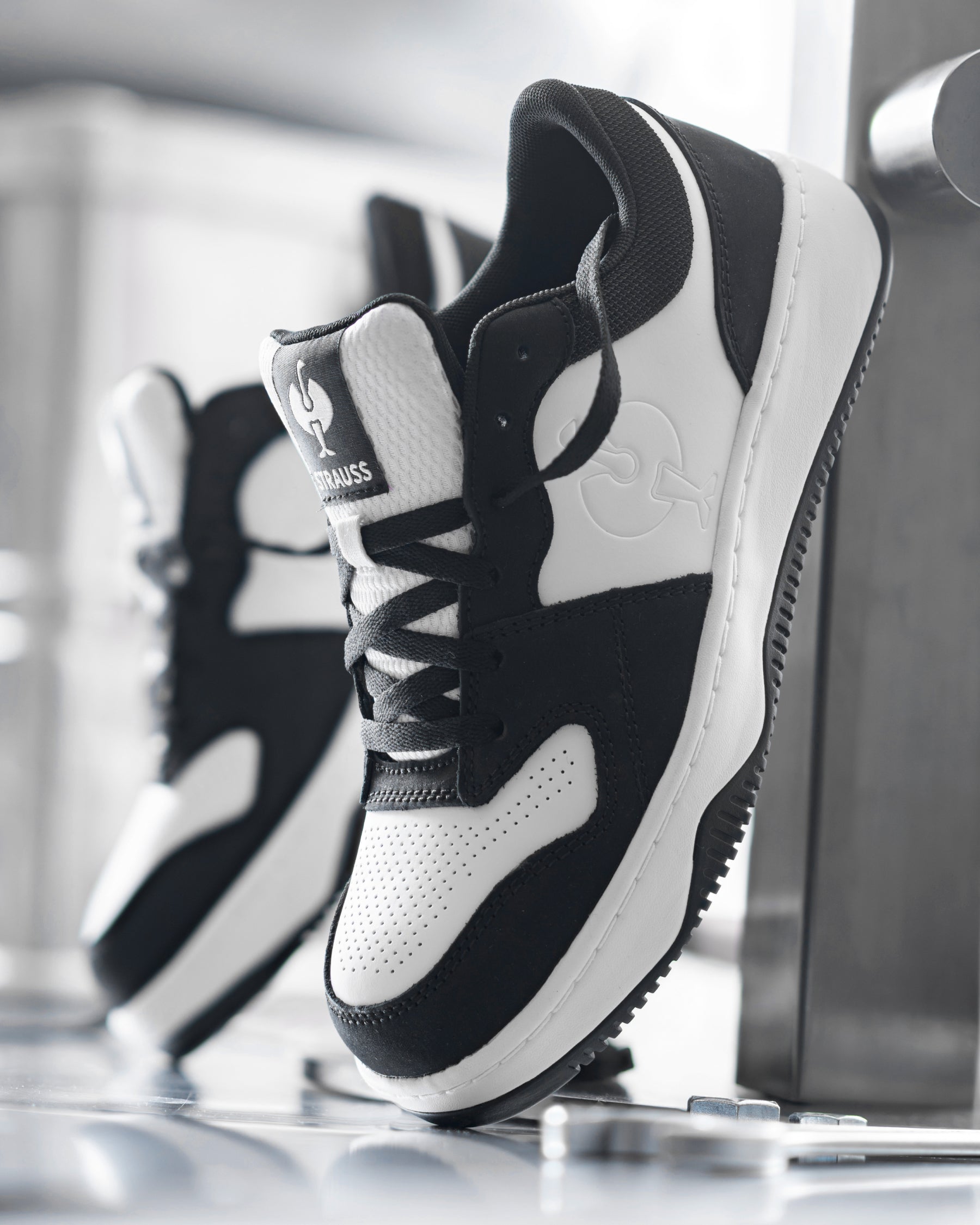 STRAUSS Eindhoven Steel Toe Work Shoe in Black and White with workwear in a jobsite scene