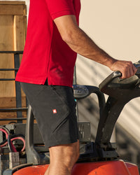 Engelbert Strauss utility cargo work shorts in black in an outdoor-style lifestyle view, showing the shorts as part of a functional work outfit.