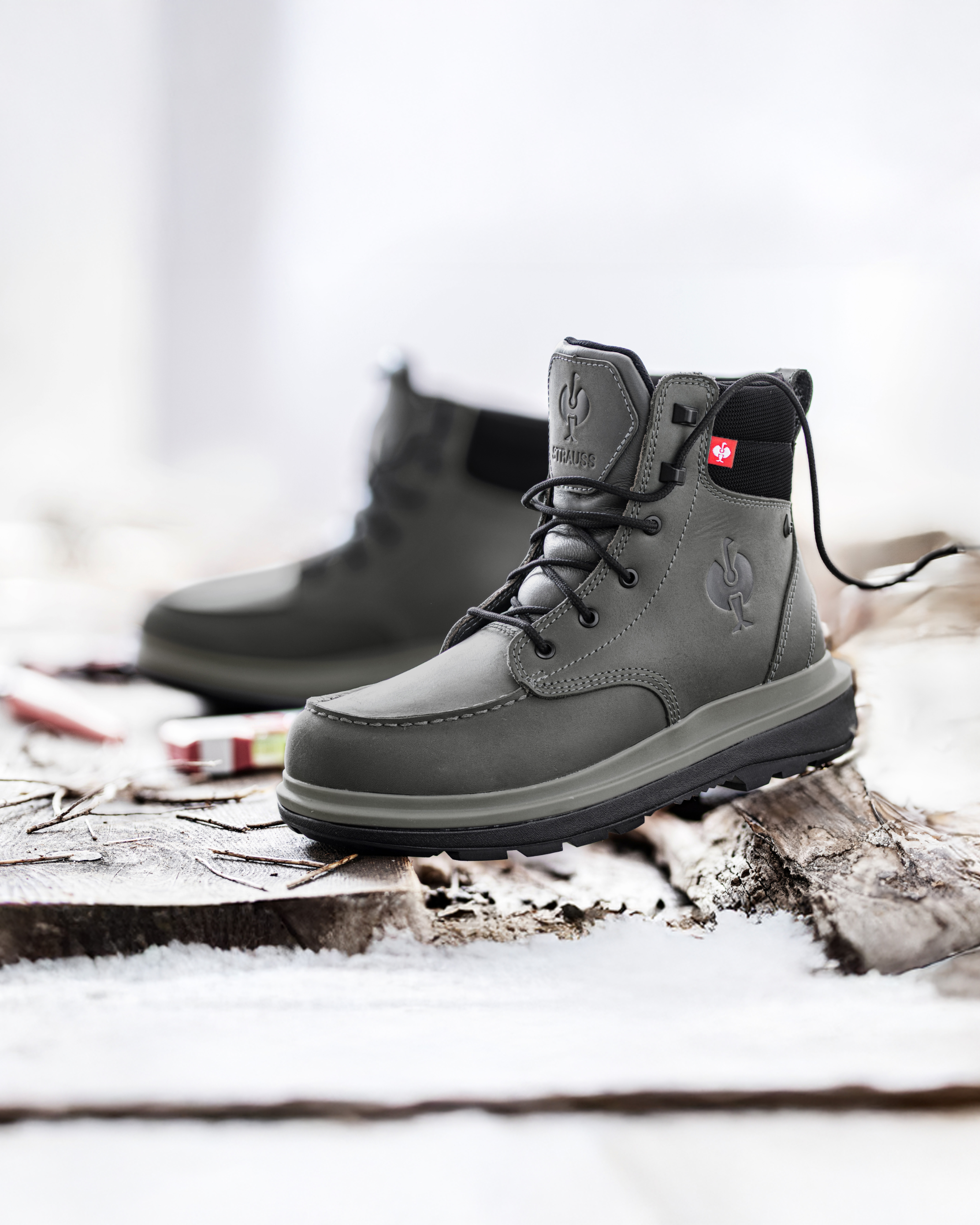 Gray boots with a brand logo on a wooden, snowy background