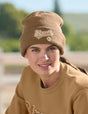 Woman wearing a brown beanie and sweatshirt with 'Strauss' branding outdoors.