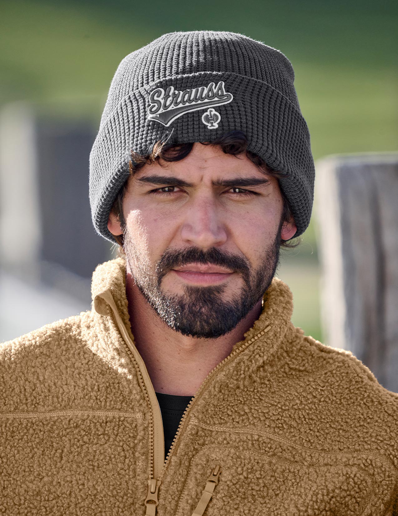 Man wearing a beanie with a logo and a jacket outdoors