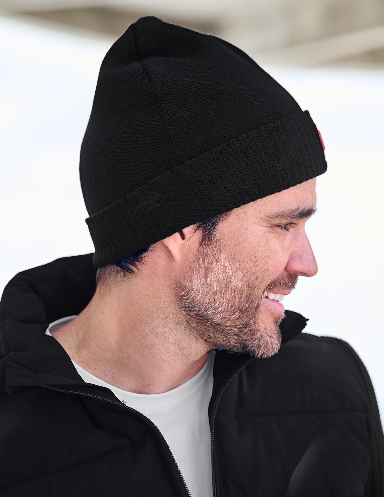 Man wearing a black beanie and black jacket with a blurred background