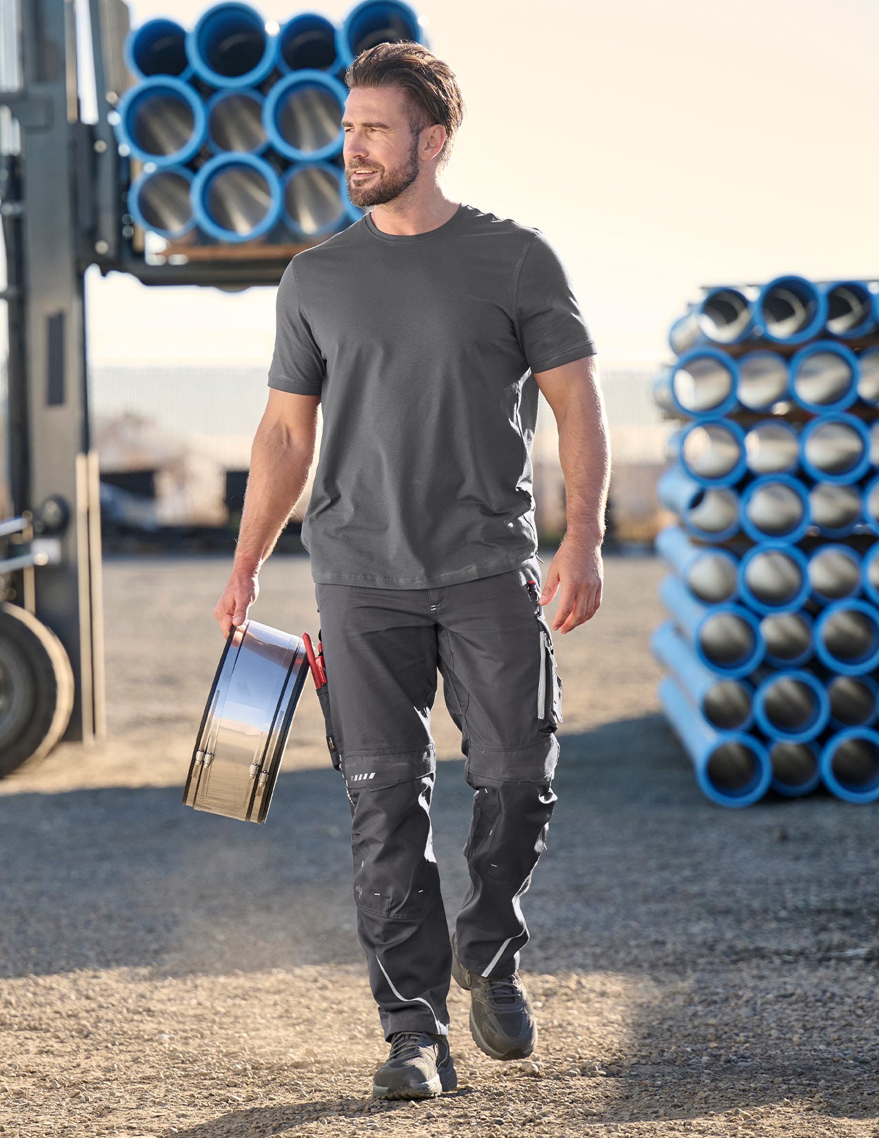 Man wearing grey pants and shirt, holding an object
