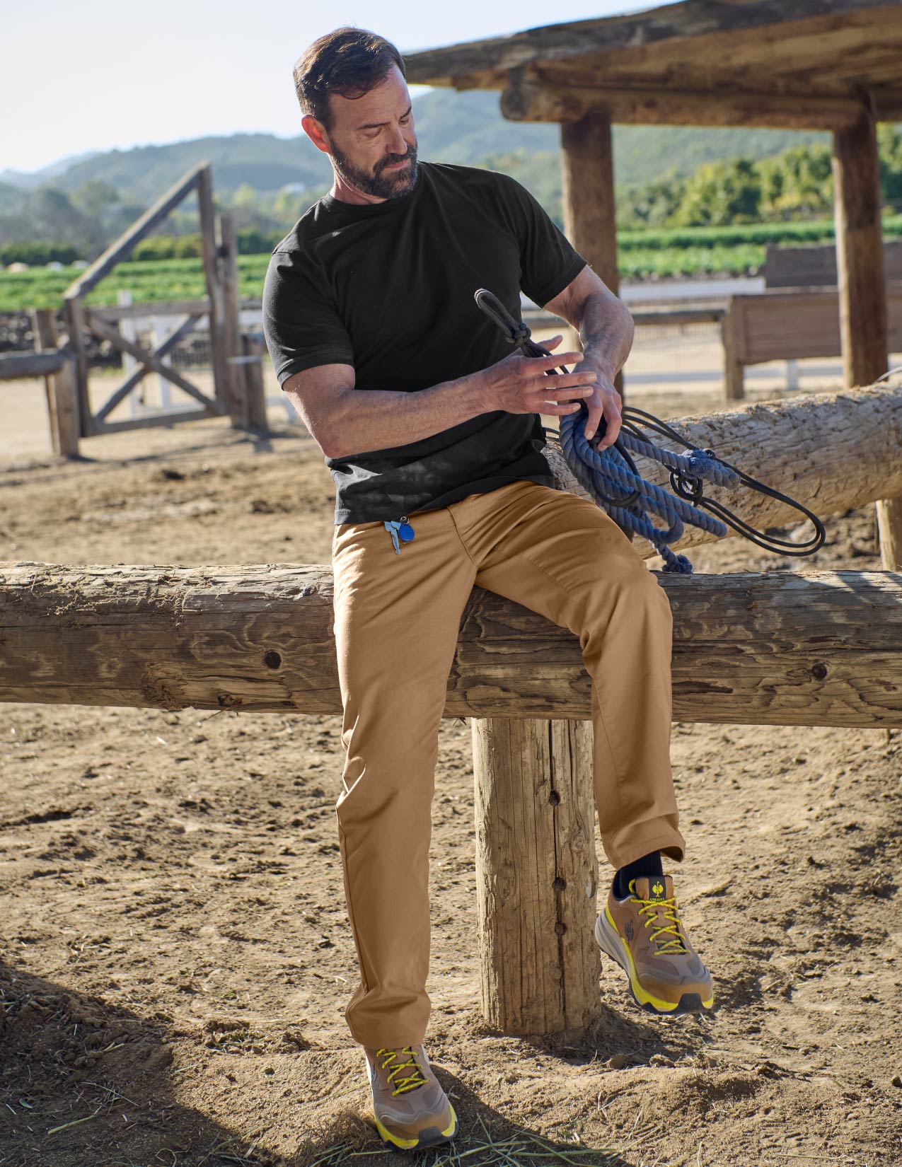 Man sitting on a wooden log outdoors with a scenic background