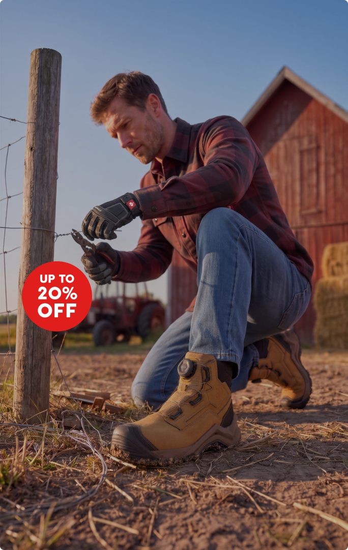 A man kneeling in front of a fence. He is wearing a red and grey flanel work shirt, a denim jeans, a pair of work boots and gloves. He is cutting a wire with a tool. At the top right corner there is a red circle with "up to 20% off" written inside.