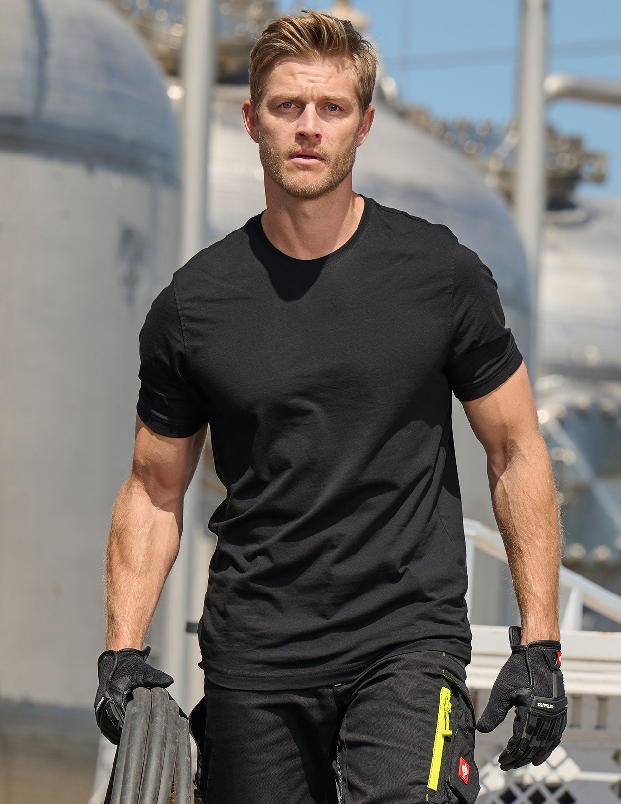 Man in black t-shirt and pants holding a cable.