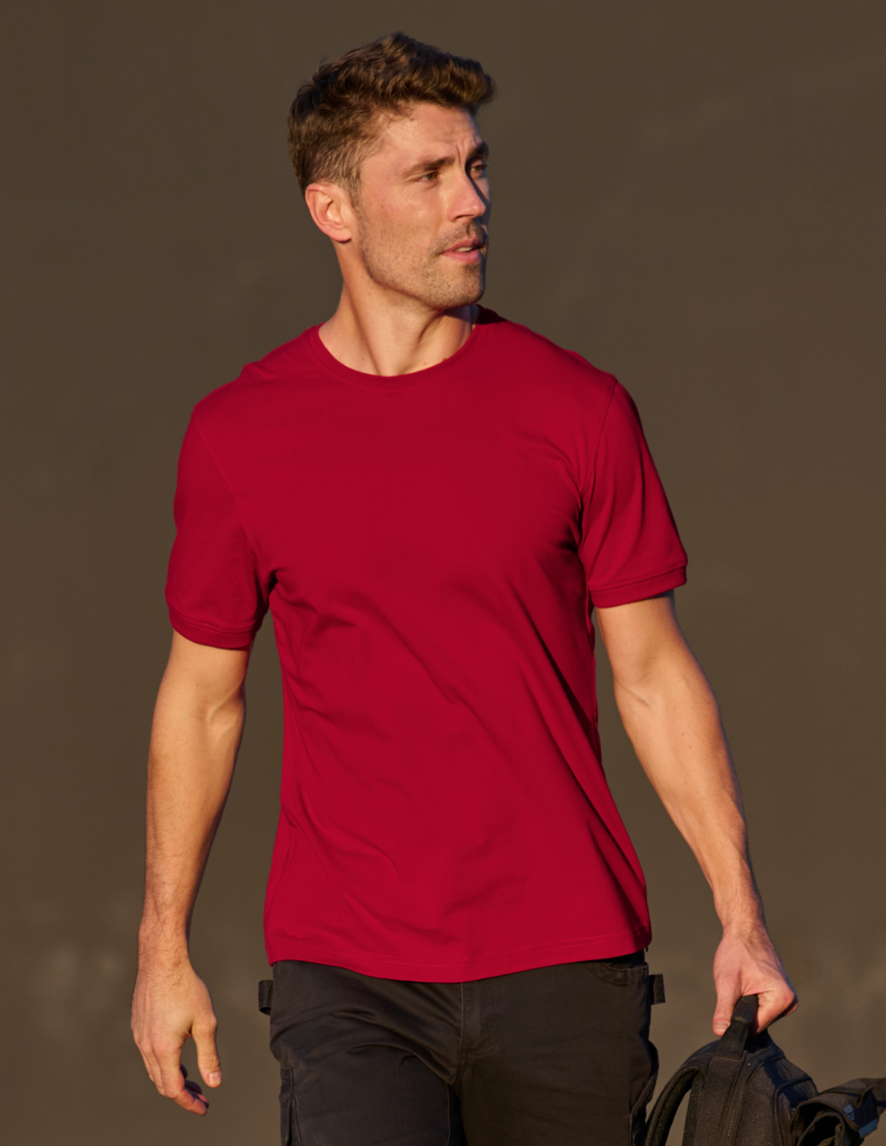 Man wearing a red t-shirt against a brown background