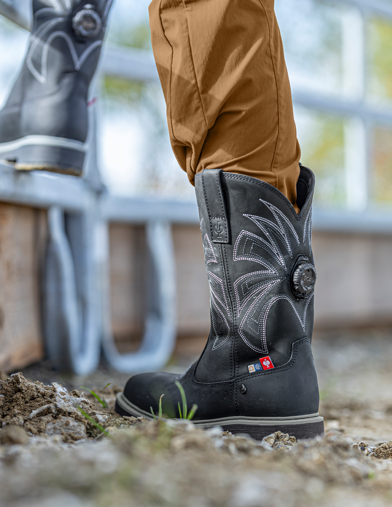 Black boot with decorative patterns on a blurred outdoor background