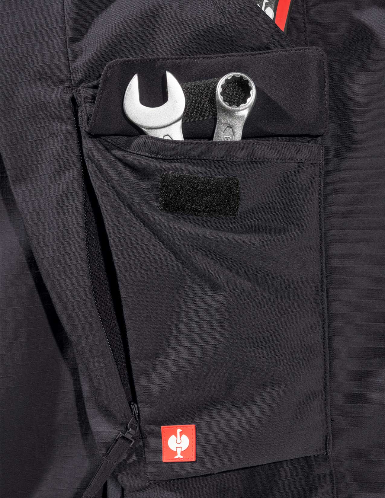 Black pant pocket with tools and a visible brand logo.