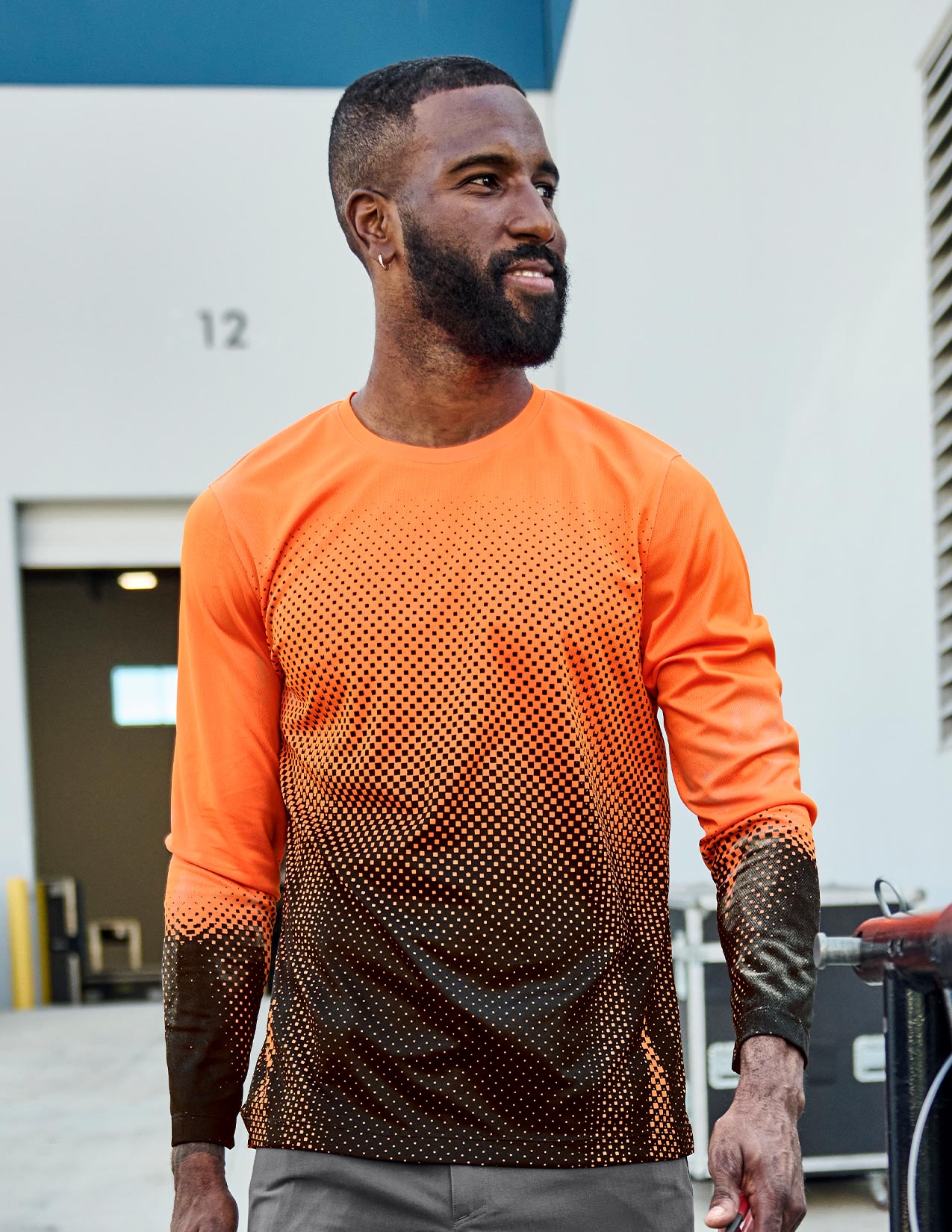 Man wearing an orange and black patterned long-sleeve shirt outdoors.