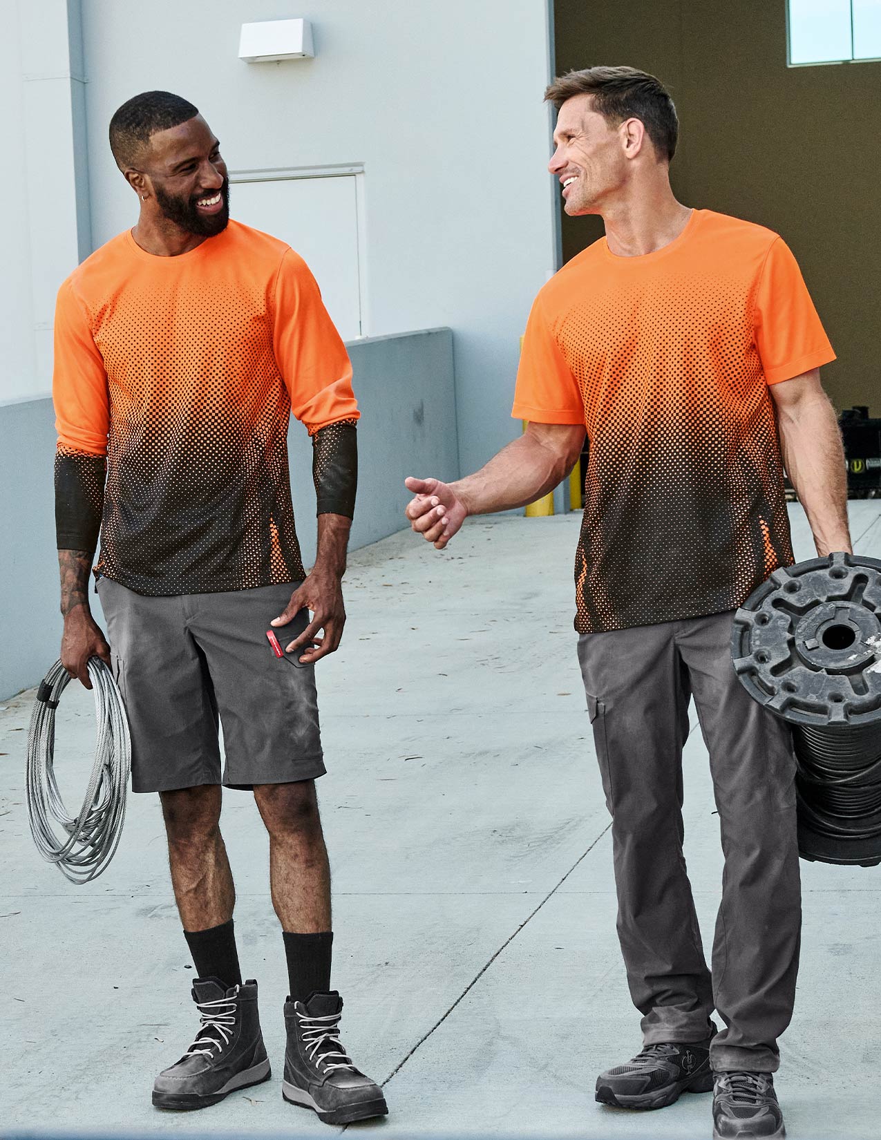 Two men wearing orange and gray athletic outfits standing outdoors.