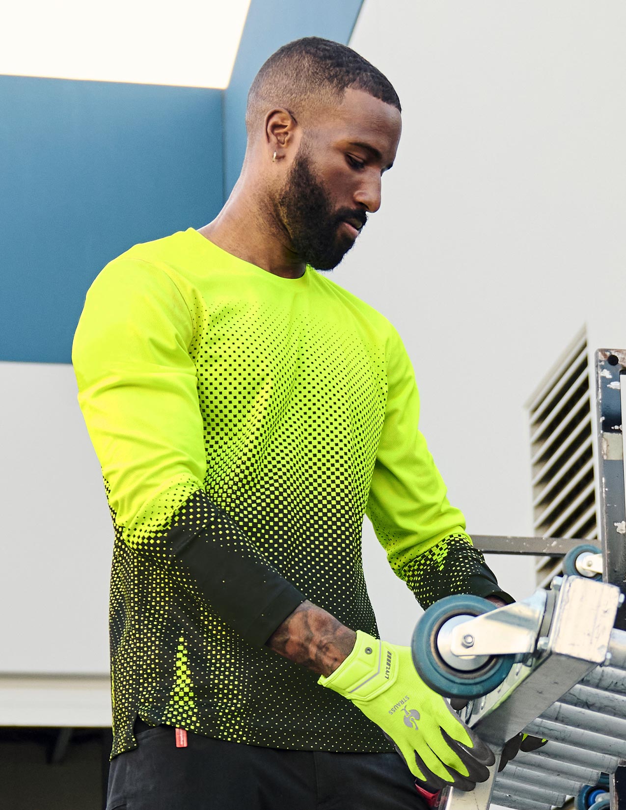 Person wearing a bright yellow long-sleeve shirt and gloves, working on a metal surface.