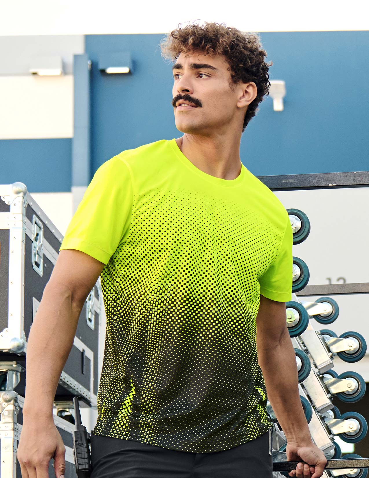 Man wearing a bright yellow athletic shirt with a pattern, standing outdoors.