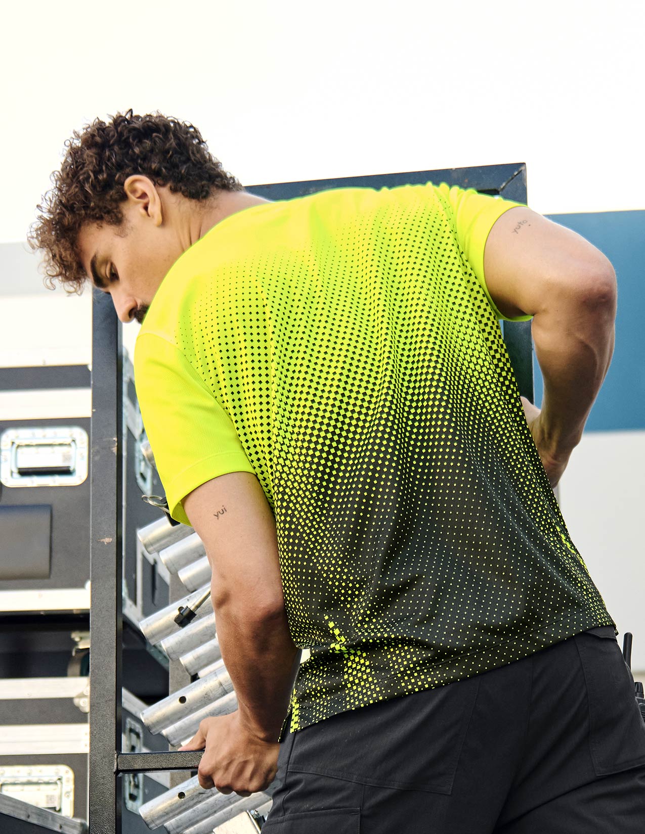 Person wearing a bright yellow and black patterned shirt outdoors