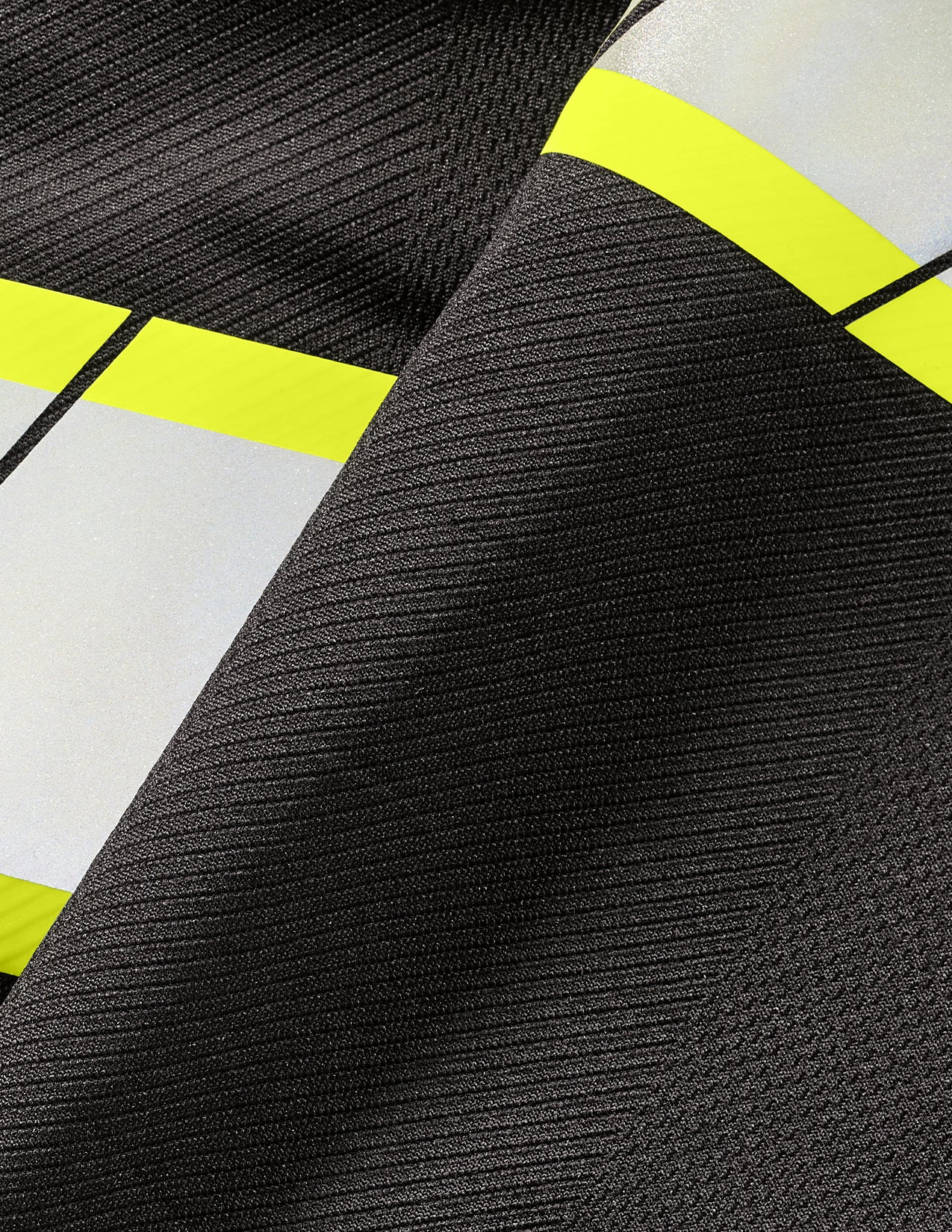 Close-up of a fabric with reflective stripes in black, white, and yellow.