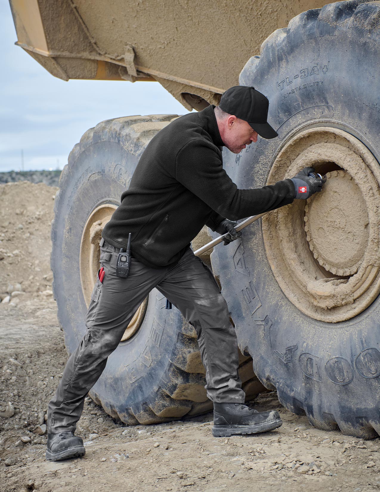 Person working on a large tire of a construction vehicle in an outdoor setting