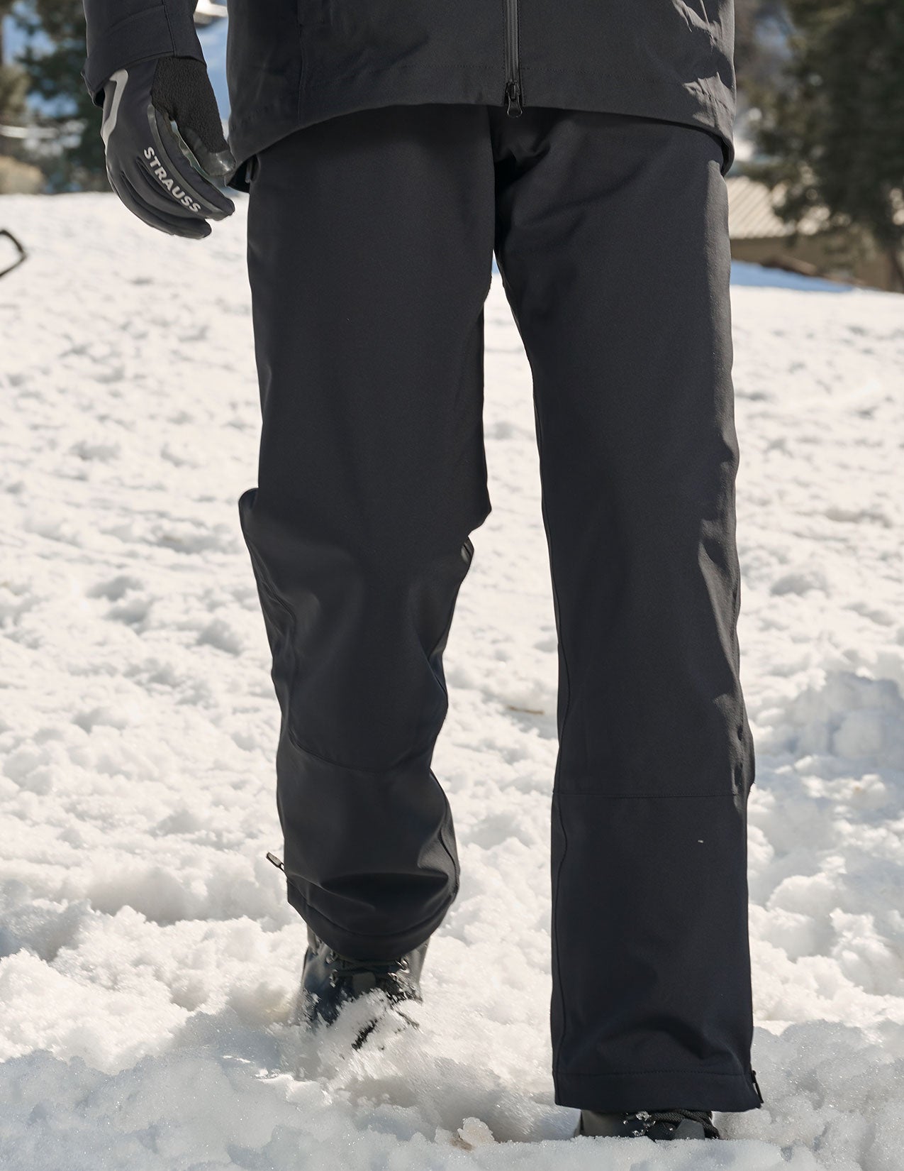 Person wearing black snow pants standing in a snowy landscape.