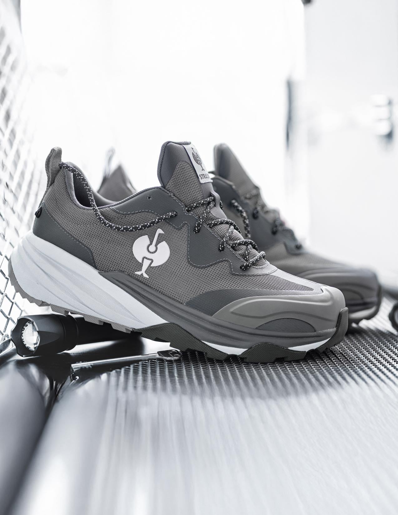 Gray sneakers with a STRAUSS logo on a metallic surface