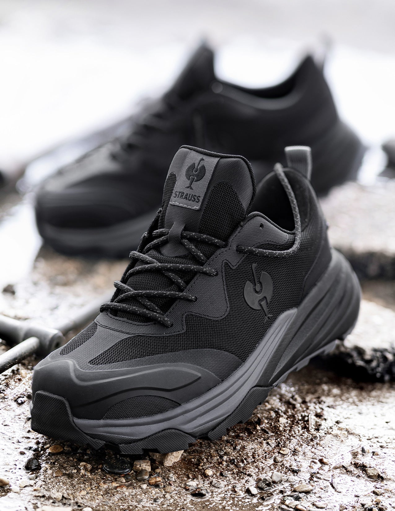Black hiking shoes with STRAUSS logo on a textured surface