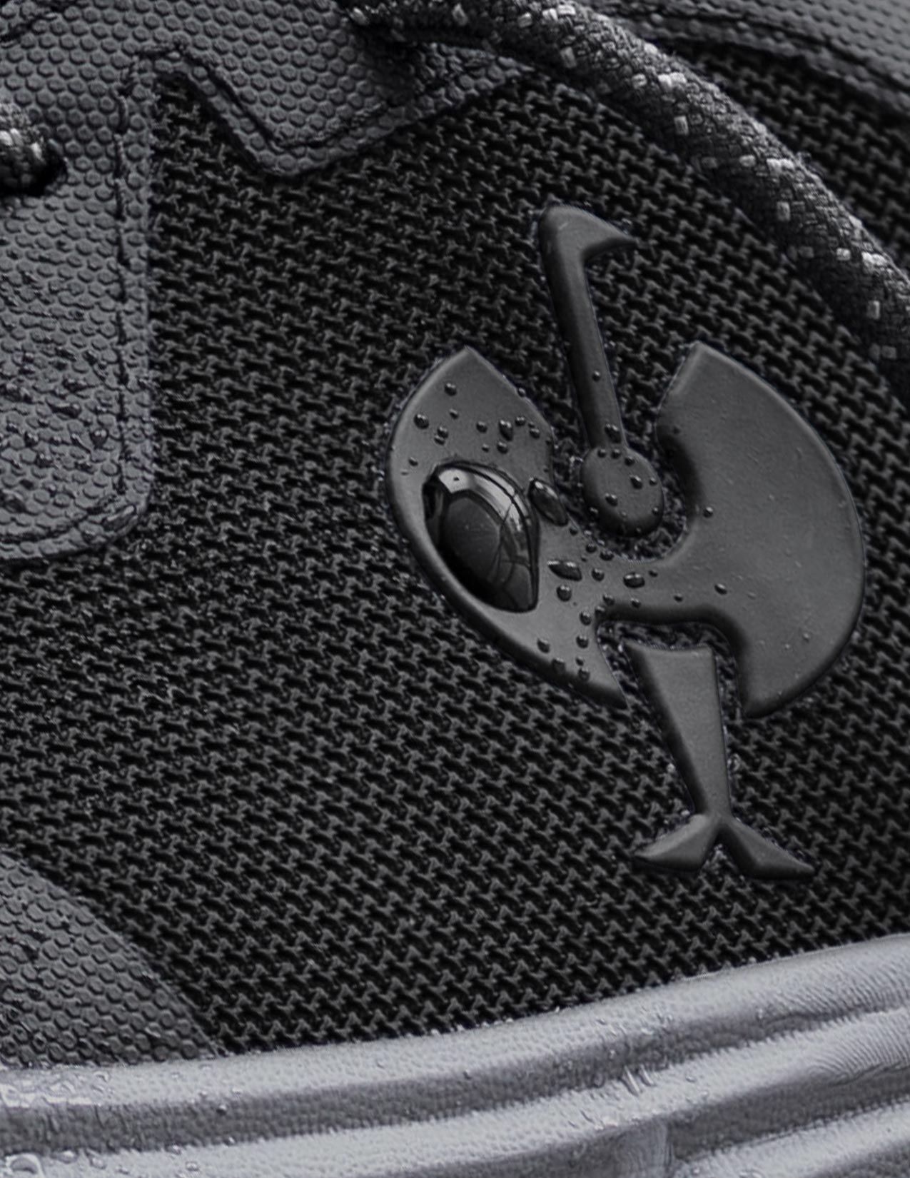 Close-up of a black textured surface with a STRAUSS logo on a shoe.