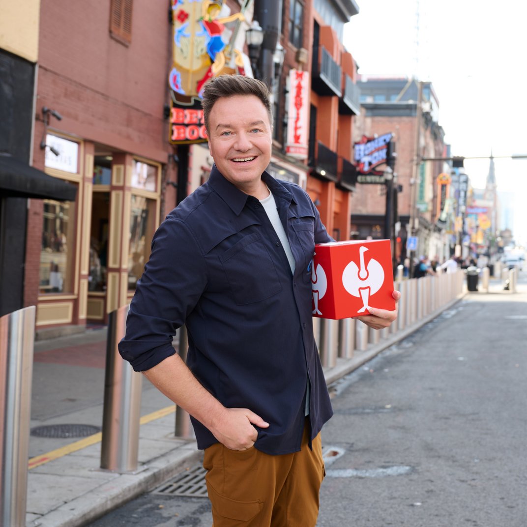A picture of Henning Strauss holding a red Strauss cube in his hands