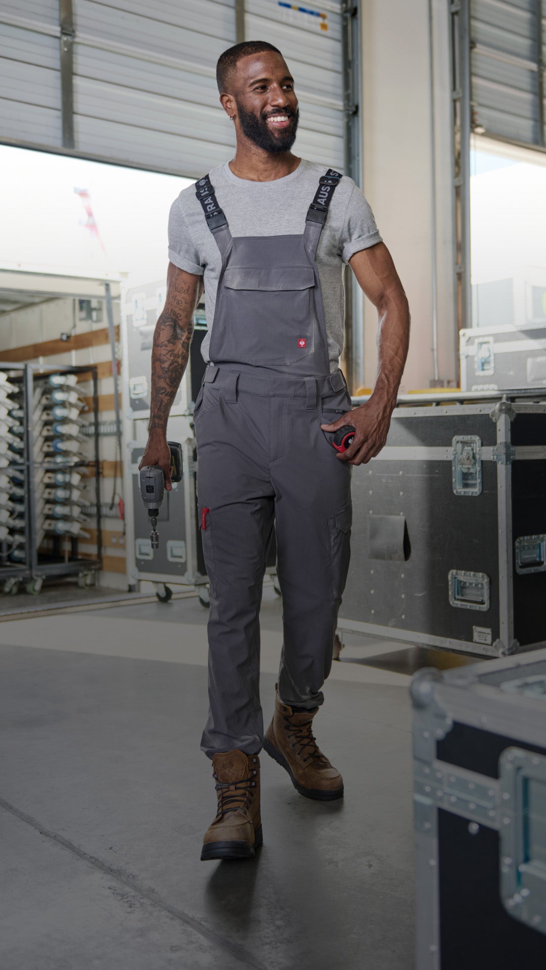 Man walking in warehouse with hardcases in grey bib
