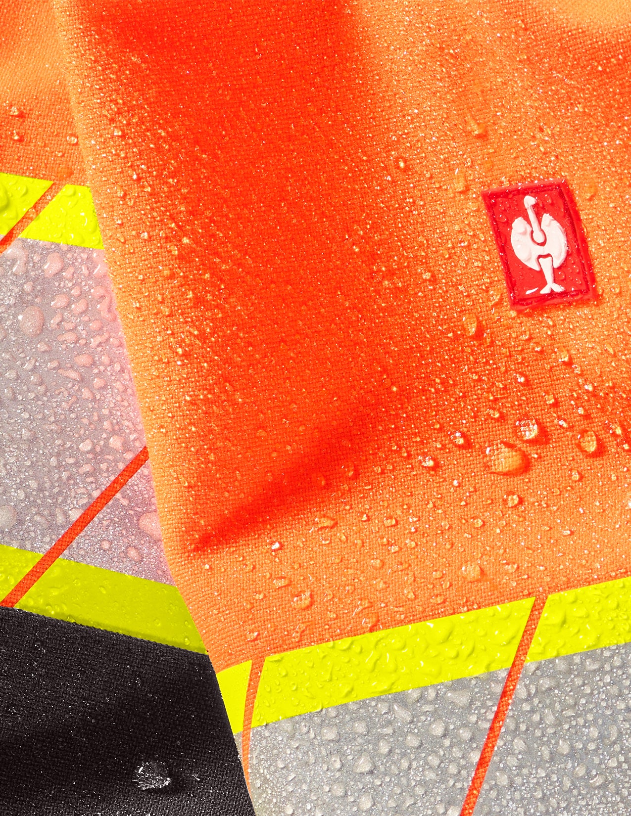 Close-up of an orange jacket with a Strauss logo on a textured surface