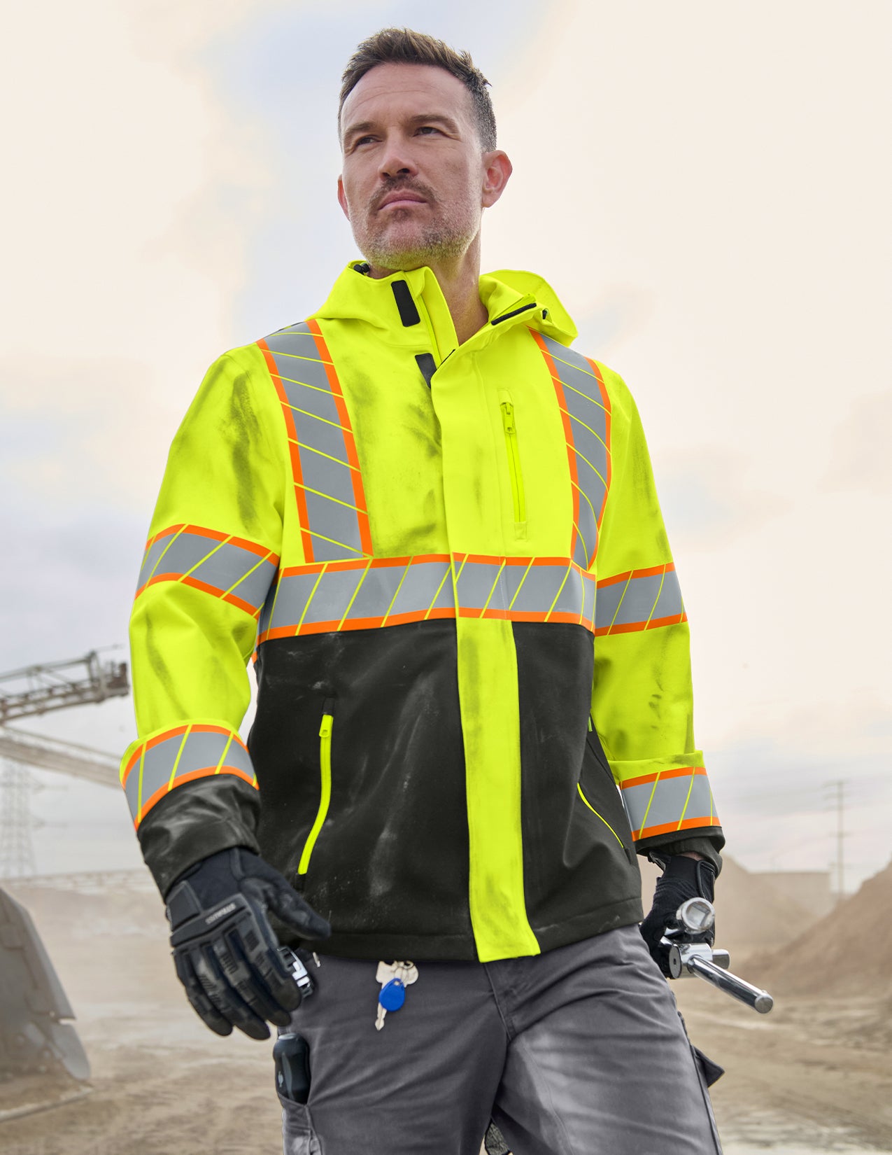 Person wearing a high-visibility safety jacket with reflective stripes outdoors.