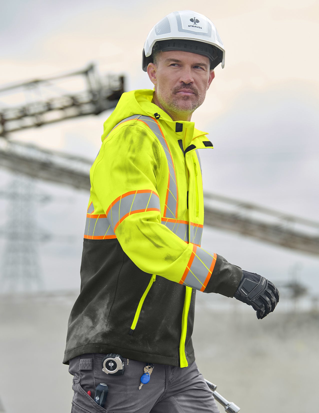 Person wearing a high-visibility safety jacket and hard hat on a construction site.