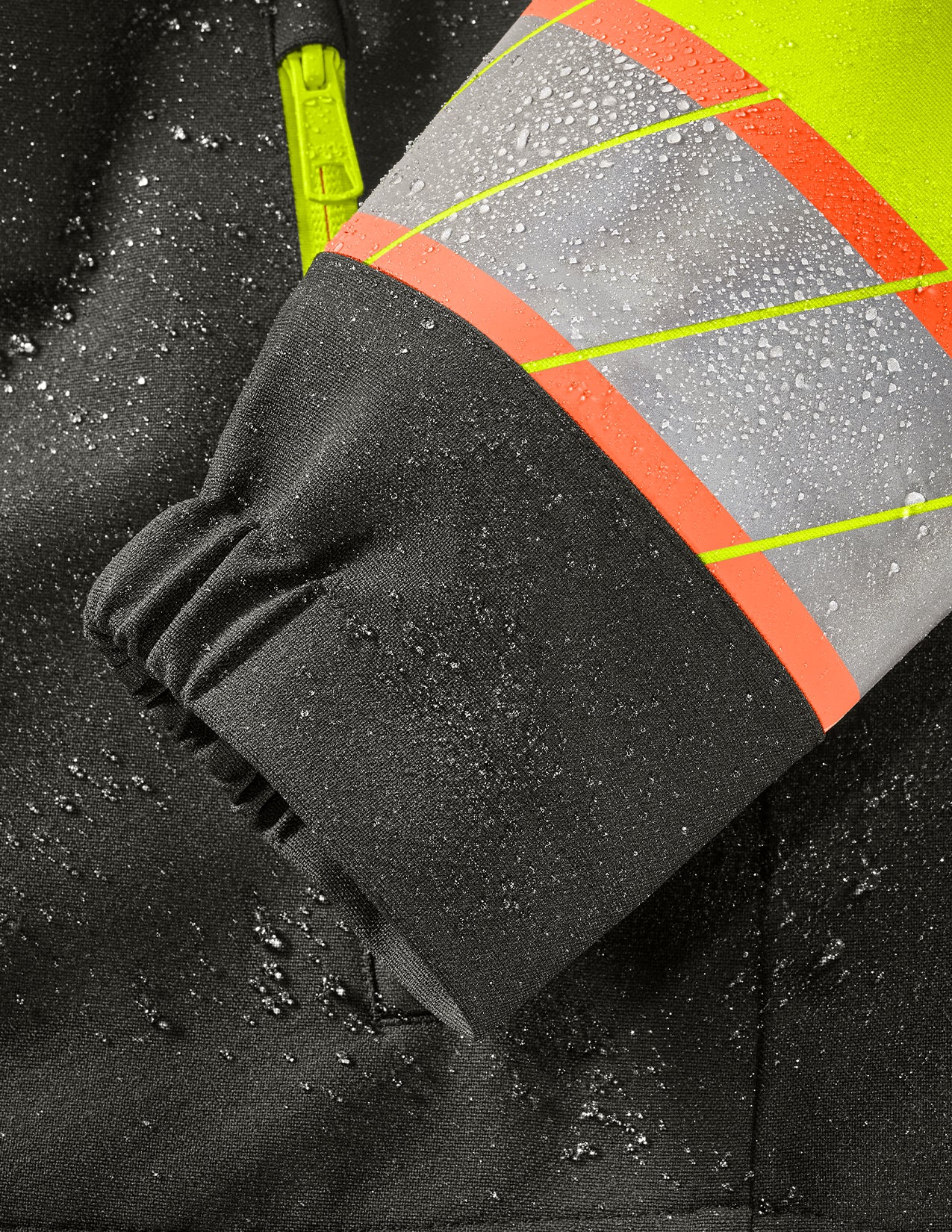 Close-up of a black jacket with reflective orange and yellow stripes on a dark background