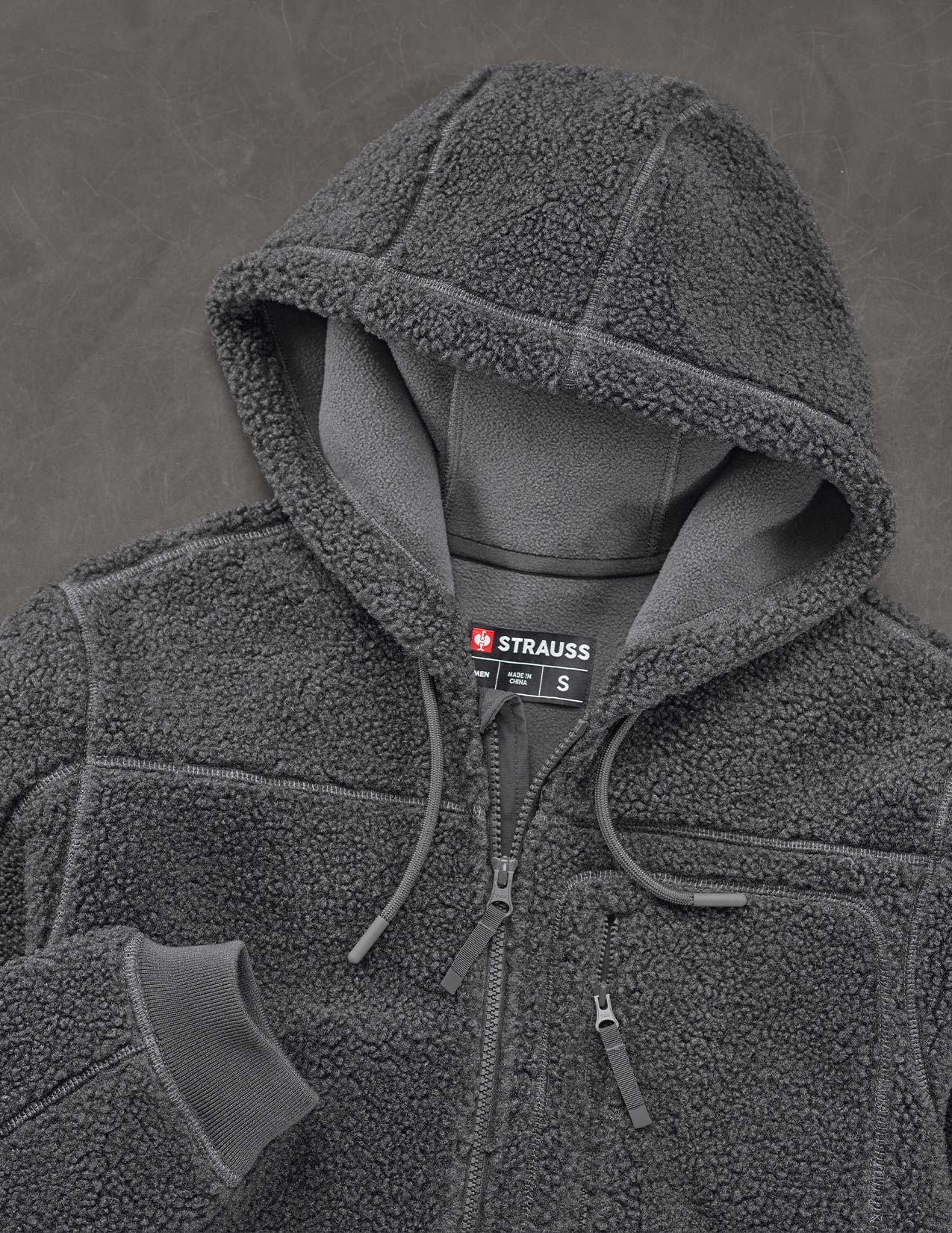 Dark gray fleece jacket with a hood on a gray background, featuring the Strauss brand.