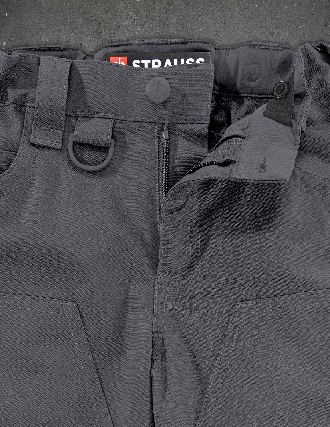 Close-up of dark gray tactical pants with visible branding on a textured background